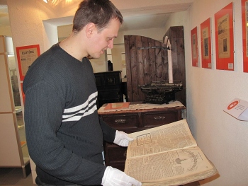 Arhivaarikindad käes, lehitseb Raivo Suni 100 aasta vanust Ristirahwa Pühhapäewa lehte, mille annetas näituse tarbeks kohalik elanik Juhan Reimann. Foto: Merje Talvik