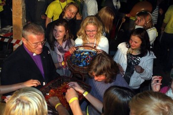 Kirikunoorte päevi tervitama tulnud peapiiskop Andres Põder sai korraldajatelt magusa ülesande jagada sünnipäevatordi asemel kommi. Foto: Pilleriin P. Kalmus