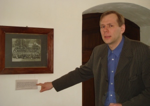 Arhivaar Janis Tobreluts näitab Viljandi Pauluse kiriku Jaan Lattiku mälestustoa seinalt ajaloolist fotot 1914. a usuõpetuse kursusest Viljandis, mis toimus paar kuud enne Esimese maailmasõja puhkemist.Foto: Liina Raudvassar