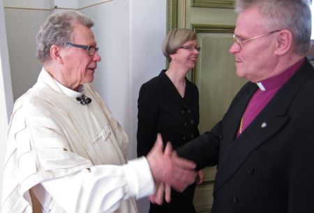 Peapiiskop Andres Põder õnnitleb EELK koostöömedali saanud Veli-Matti Hynnineni, taamal Camilla Hynninen.  Heikki Jääskeläinen